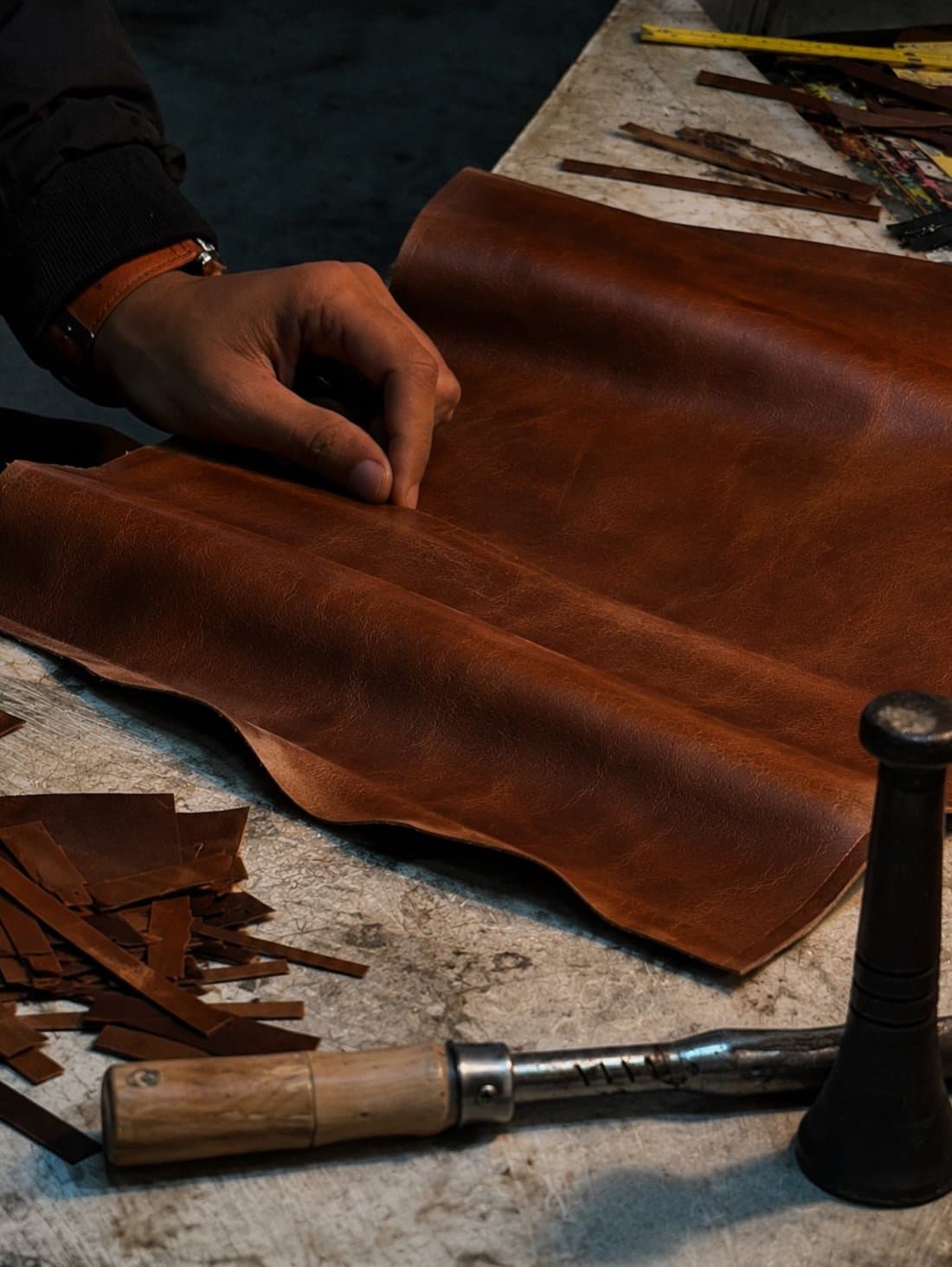A craftsman working a tanned hide by hand at the bench