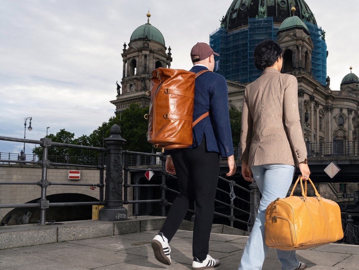 Two travellers crossing the Spree by the Berliner Dom, carrying the weekender as a backpack and as a duffel